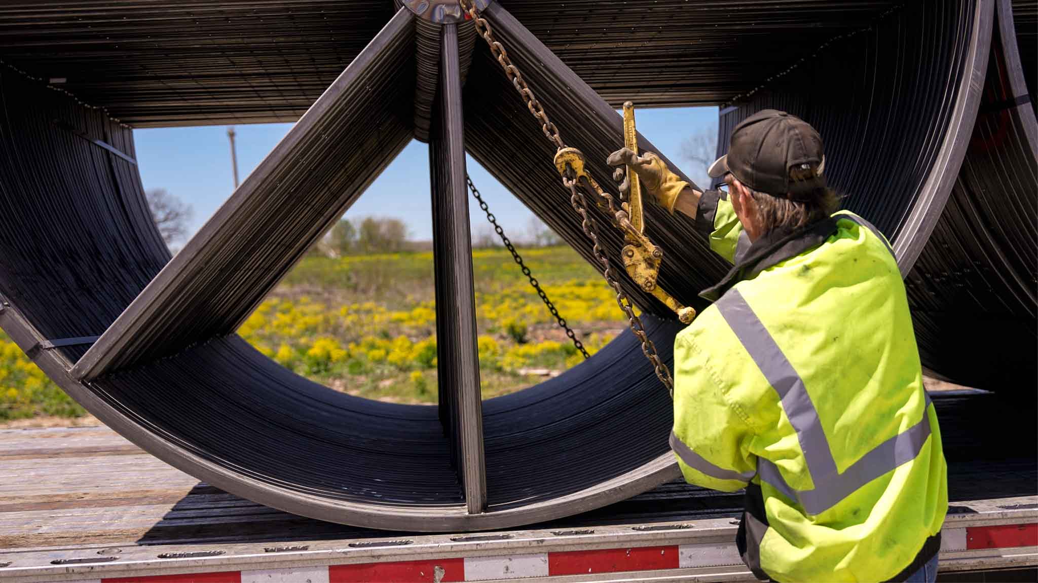 chains securing steel reels on trailer being tightened